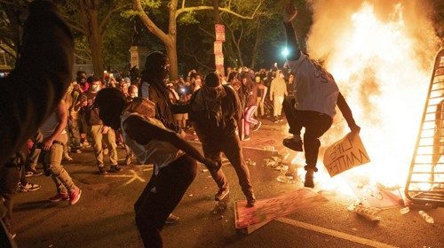 TOPSHOT - Protesters jump on a street sign near a burning barricade during a demonstration against ...