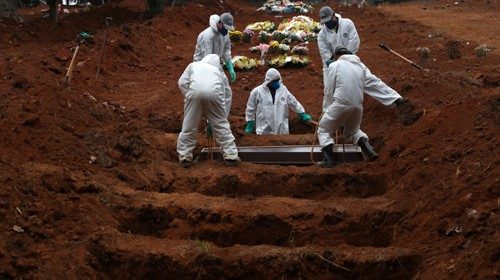 Gravediggers wearing protective suits bury the coffin of 48-years-old Jose Soares, who died from the ...
