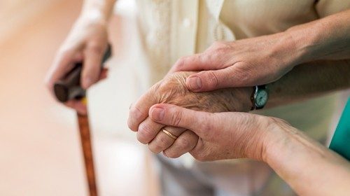 Nurse consoling her elderly patient by holding her handskk.jpg