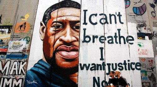 Men walk past a mural showing the face of George Floyd, an unarmed black man who died after a white ...