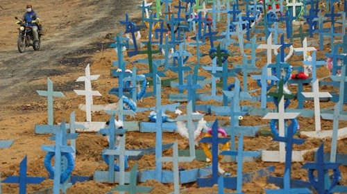 A gravedigger drives his motorcycle at the Parque Taruma cemetery, amid the coronavirus disease ...