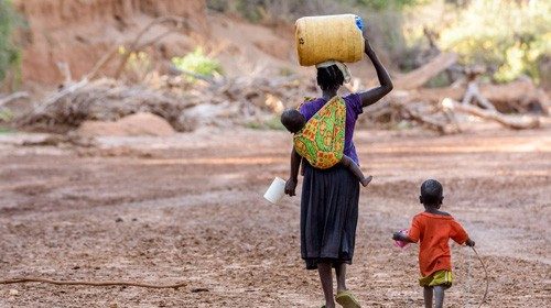 Children make the long walk home with containers of polluted water they scooped from holes they dug ...