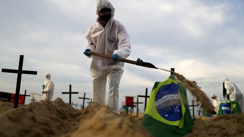Activists of the NGO Rio de Paz in protective gear dig graves on Copacabana beach to symbolise the ...