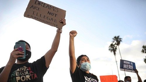 People hold signs and a woman raises her fist during a rally in support of the Supreme Court's ...