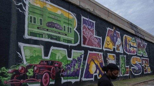 TOPSHOT - A woman walks past a 'Black Wall Street' mural during Juneteenth celebrations in the ...
