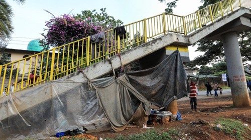 epa08496809 A refugee (R), stands under a footbridge where he and other refugees sleep next to a ...