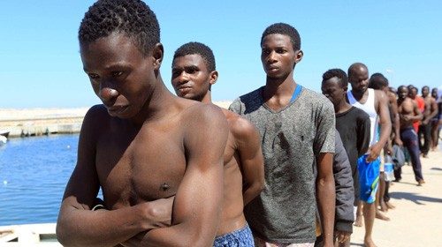 Illegal migrants from Africa, attempting to reach Europe, walk towards a detention center off the ... Illegal migrants from Africa, attempting to reach Europe, walk towards a detention center off the ...