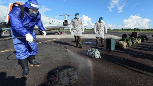 Members of the Brazilian Armed Forces disinfect luggage that arrived on a military flight at the ...