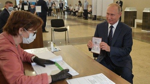 TOPSHOT - Russian President Vladimir Putin shows his passport to a member of a local electoral ...