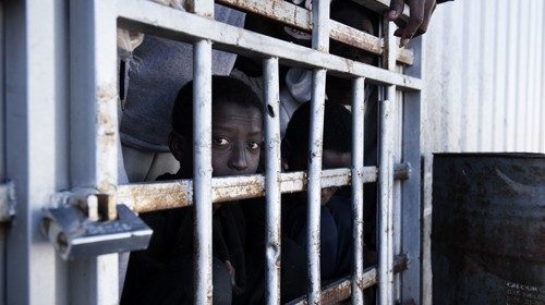 A migrant looks out from behind the bars of a cell at a detention centre in Libya, Tuesday 31 ...