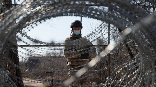 A member of the Ukrainian State Border Guard Service wearing a protective mask is seen at the ...