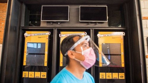 A worker wearing a protective mask and face shield stands near a cinema's ticket machine during ...