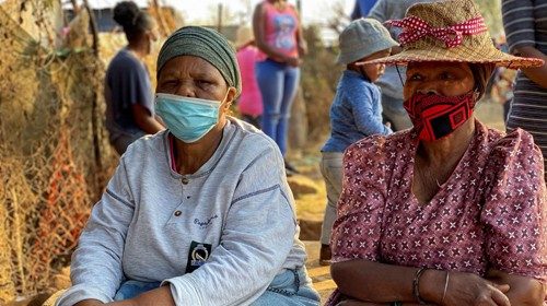 Women look on, as chefs from SA Harvest and Chefs with Compassion hand out food parcels to poor ...