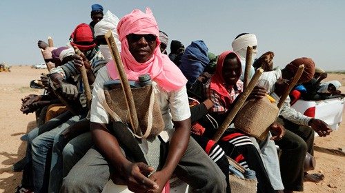 Nigeriens sit in the back of a truck, preparing to travel north towards Libya, while waiting for ...