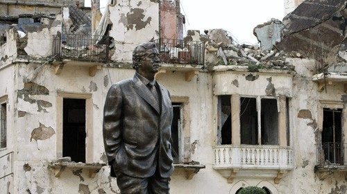La statua di Hariri tra i palazzi distrutti nel centro di Beirut (Afp)
