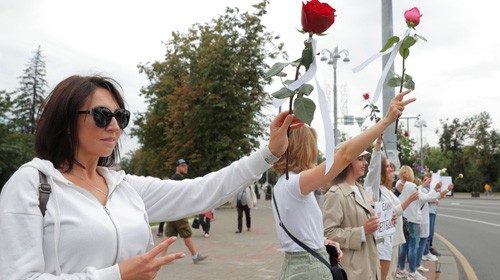 Women hold flowers while lining up during a demonstration against violence following recent protests ...