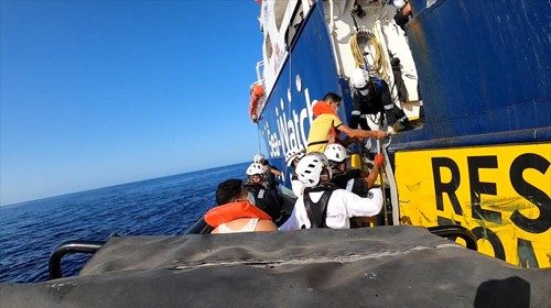 A rescued migrant enters the Sea- Watch 4 ship helped by a rescue team, at sea off the coast of ...