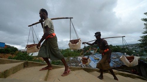 Rohingya trasportano acqua nel campo di Jamtoli in Bangladesh (Afp)