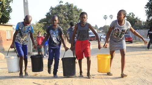 Bambini di Harare (Zimbabwe), dove la popolazione è colpita da una grave siccità, si aiutano nel portare secchi d’acqua (Epa)