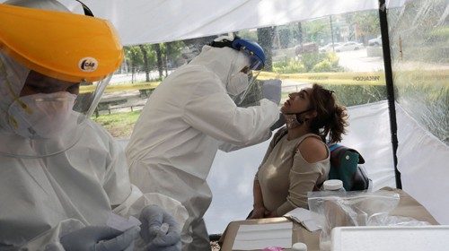 A healthcare worker wearing personal protective equipment (PPE) takes a swab sample from a woman for ...
