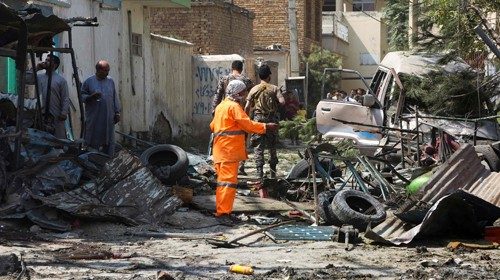 Afghan security personnel (back) inspect the site of an explosion targeting the convoy of ...