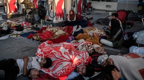 TOPSHOT - Homeless migrants and refugees sleep at a gas station after a fire destroyed Greece's ...