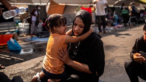 A migrant woman and a girl react after having been cleaned with water after police threw tear gas ...