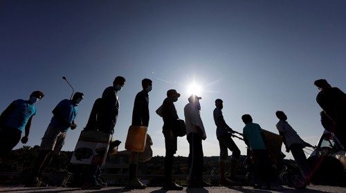 Refugees and migrants from the destroyed Moria camp line up to enter a new temporary camp, on the ... Refugees and migrants from the destroyed Moria camp line up to enter a new temporary camp, on the ...