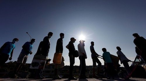 Refugees and migrants from the destroyed Moria camp line up to enter a new temporary camp, on the ...