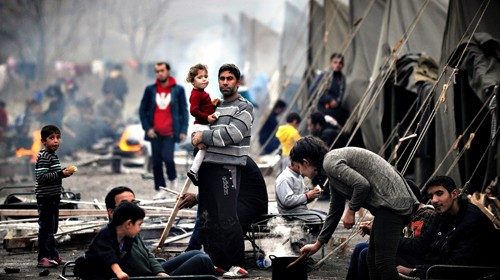 A Syrian refugee holds a baby in a refug...A Syrian refugee holds a baby in a refugee camp set in ...