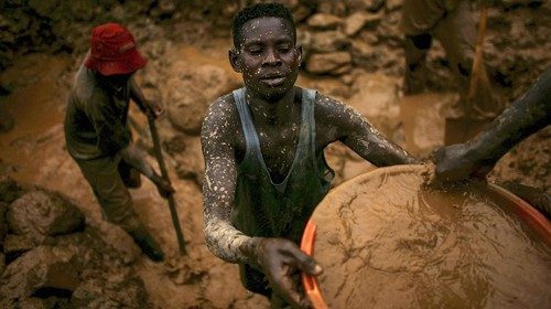 Uomini setacciano secchi di fango mentre cercano oro in una miniera industriale abbandonata a Mongbwalu, in Congo