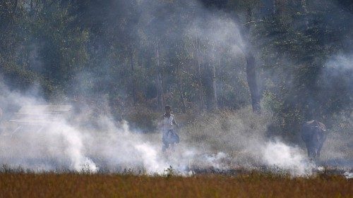 In this photograph taken on October 22, 2020 a man walks through a burning straw stubble on a field ...