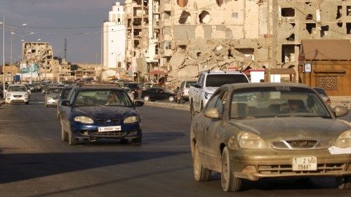Cars drive near shell-pocked buildings in Libya's eastern coastal city of Benghazi on October 23, ...