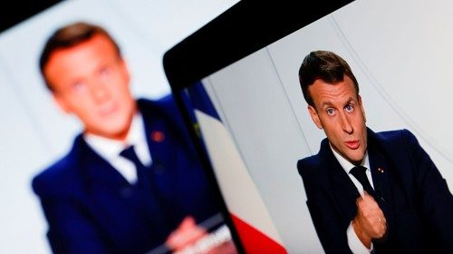 French President Emmanuel Macron is seen on screens as he addresses the nation about the state of ...