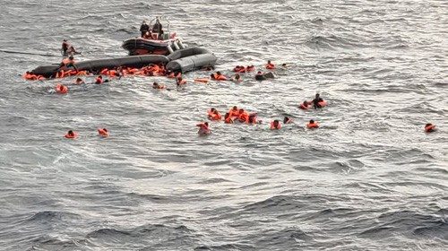A still image taken from a video shows migrants at sea waiting to be rescued by Spanish search and ...