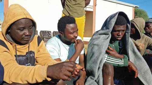 Migrants, who survived a deadly shipwreck, gather on a sandy beach on the coast of al-Khums, a port ...