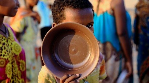 An Ethiopian child who fled war in Tigray region, carries his plate as he queues for wet food ration ...