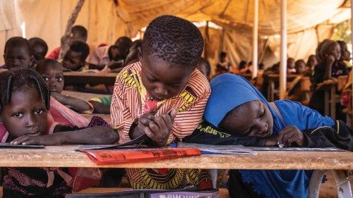 Primary schoolchildren write on their board in a classroom under a tent put in place to face the ...