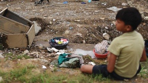 A child takes a break from cleaning his house following the flood brought by Typhoon Vamco, in ...