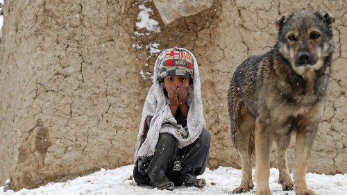An internally displaced Afghan boy sits outside his shelter during snowfall in Kabul, Afghanistan ...