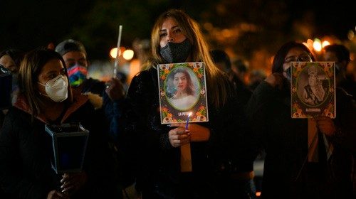 People hold photos during a vigil in memory of women murdered before the International Day of No ...
