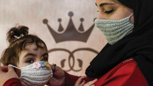 Nouran Faraj, a 24-year-old Palestinian, holds her niece as she dons a handmade crochet wool mask ...