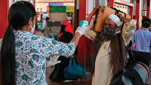 A health worker checks the body temperature of a passenger during Covid-19 coronavirus screening ...