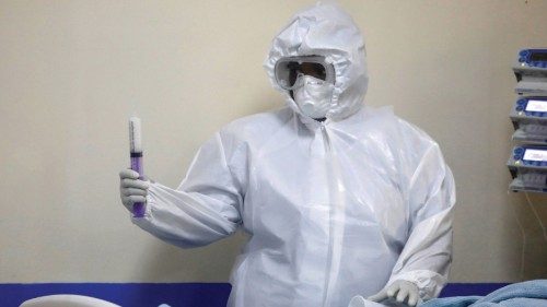 FILE PHOTO: A member of the medical staff dressed in a protective suit holds a syringe as he treats ...
