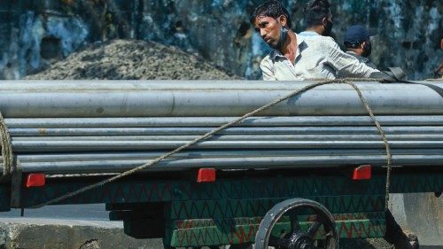 A worker pushes a hand-cart loaded with metal pipes in Mumbai on November 27, 2020. (Photo by Punit ...
