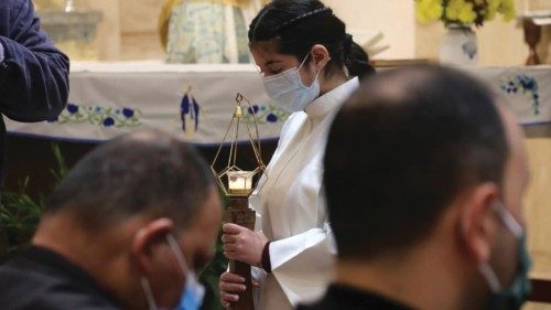 A girl, mask-clad due to the COVID-19 coronavirus pandemic, walks with a candle during mass at the ...