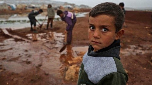 TOPSHOT - A Syrian child poses for a picture at a camp for displaced Syrians near the town of Kafr ...