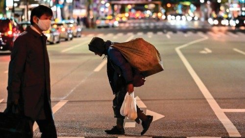 A homeless man (C) carries a bag while crossing a street at night in Tokyo's Shimbashi area on ...