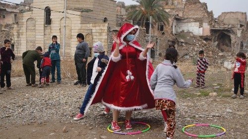 An Iraqi woman, dressed as Santa claus, plays with children, amid the spread of the coronavirus ...