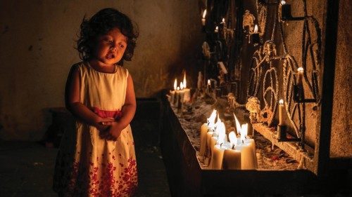 YOGYAKARTA, INDONESIA - DECEMBER 24: An indonesian Christians girl stands near candles during ...